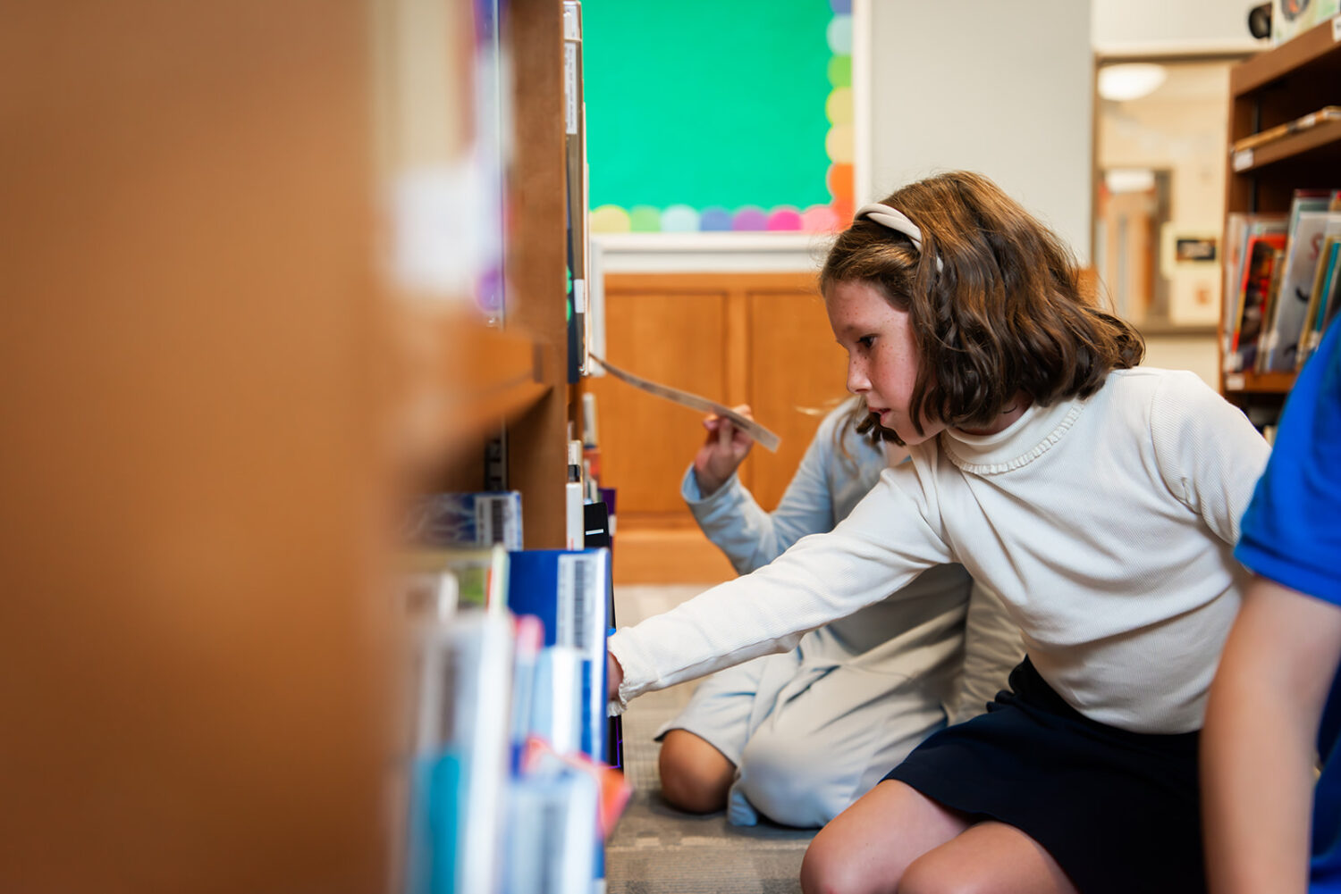 Girl looking at library books on shelves