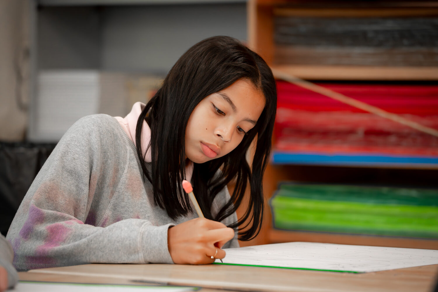girl writing on paper with a pencil