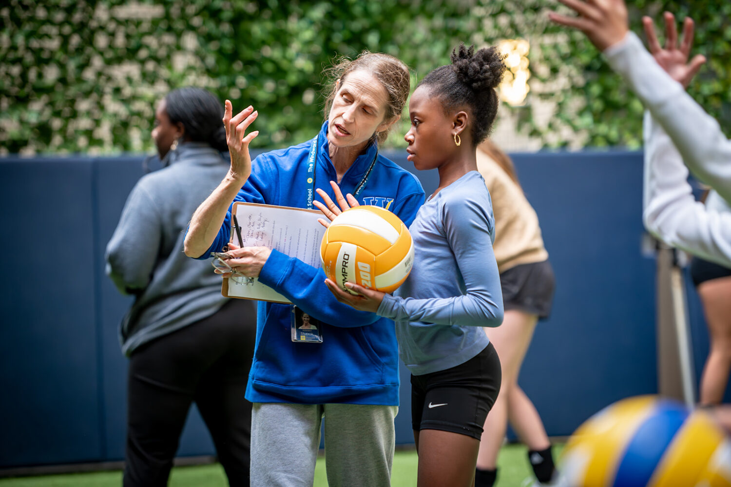 Coach teaching student about proper form in volleyball