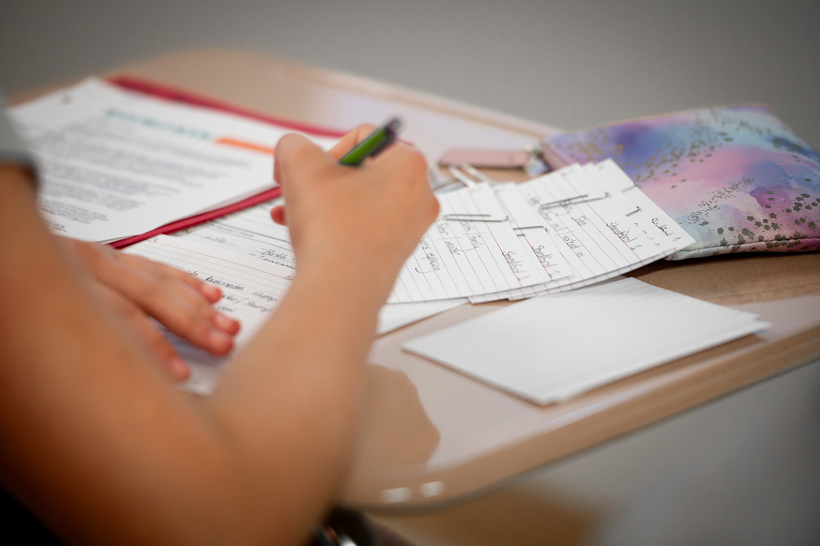 Child at student desk writing flashcards in pencil.