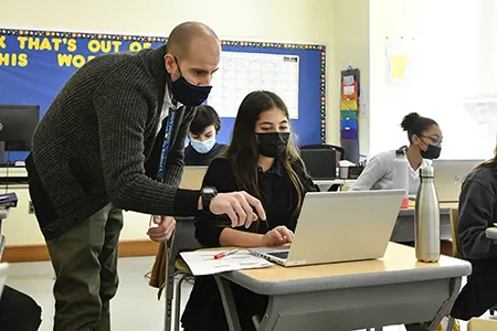 teacher wearing mask helping student