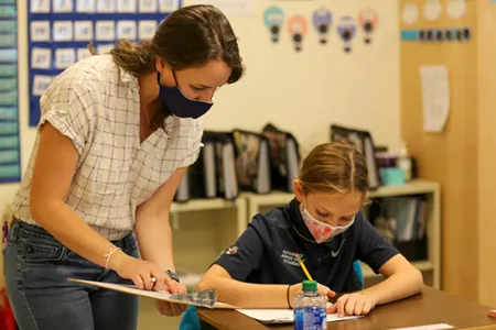 women teacher helping student at desk