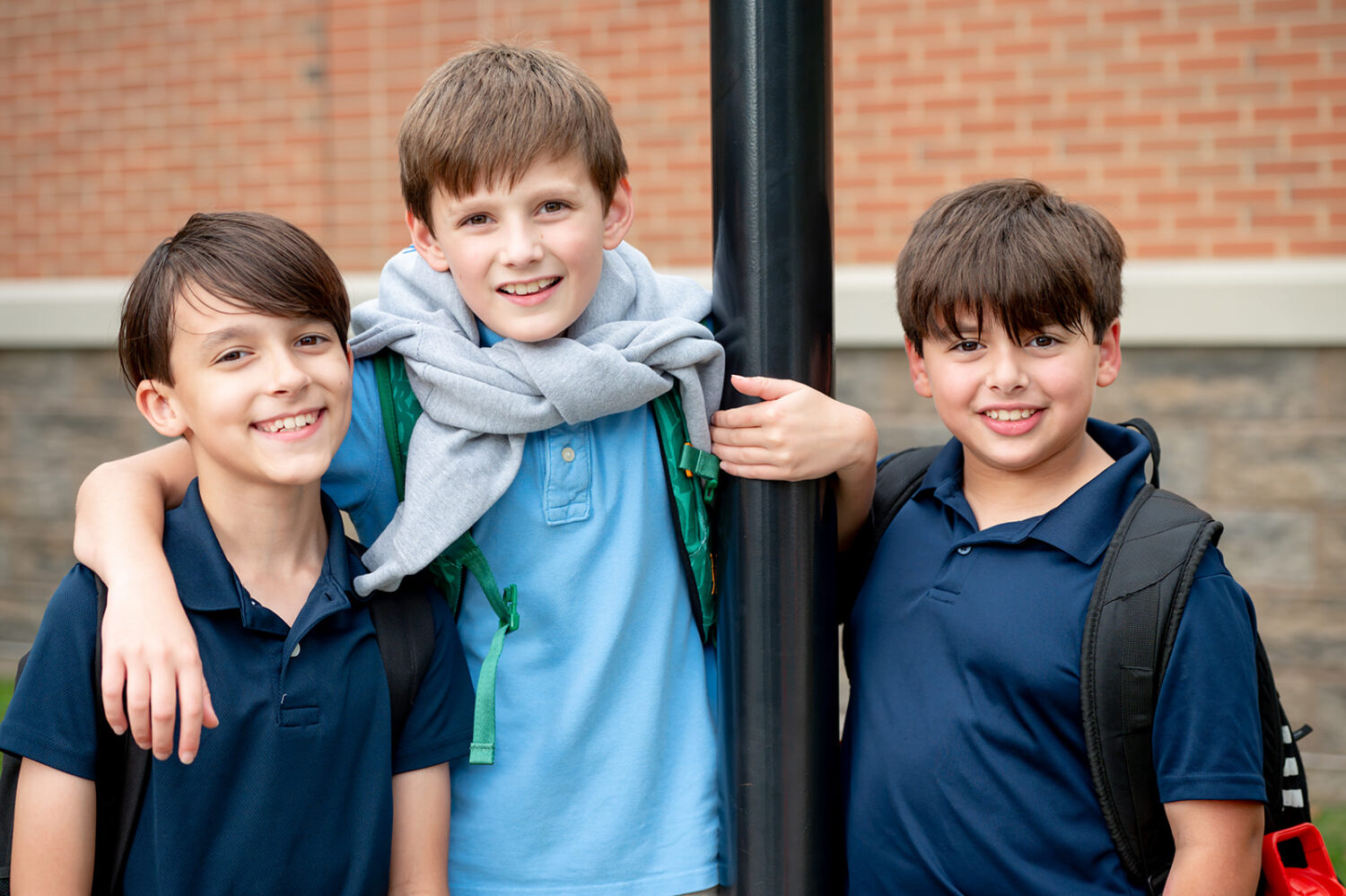 three boys wearing blue shirts smiling